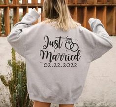 the back of a woman wearing a sweatshirt that says just married and has two rings on it