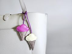 an ice cream cone charm hangs from the handle of a white leather tote bag