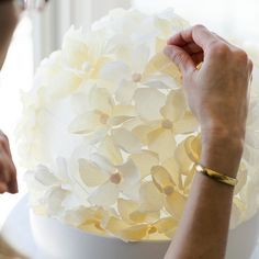 a woman is decorating a white cake with yellow flowers on the top and bottom