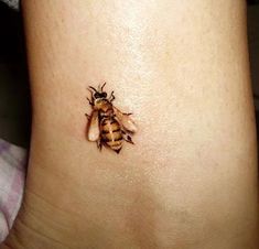 a small tattoo of a bee on the side of a woman's leg,