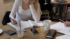 two women sitting at a table with papers and cell phones