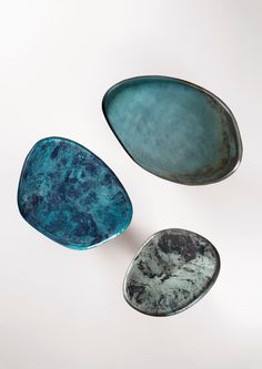 three blue bowls sitting on top of a white table next to each other in the shape of oval shapes