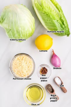 lettuce, lemon, parmesan cheese and other ingredients on a white surface