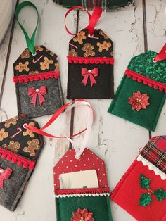 christmas ornaments made out of felt hanging on a white wooden table with red and green ribbons