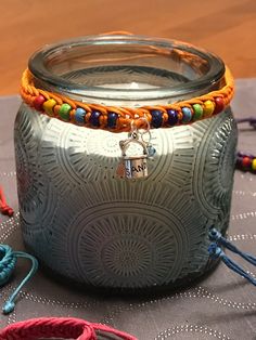 a glass jar sitting on top of a table covered in bracelets and other items