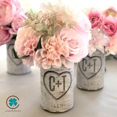 three mason jars filled with pink flowers on top of a white cloth covered tablecloth