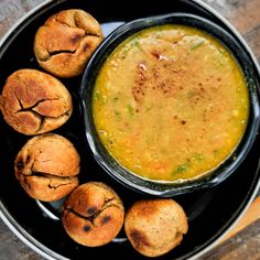 a black bowl filled with soup next to muffins