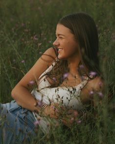 a woman is sitting in the grass and smiling