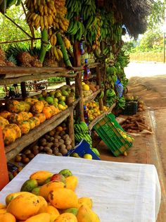 there are many fruits and vegetables on display at the market stall, including bananas, melons, pineapples, oranges, and other fruit