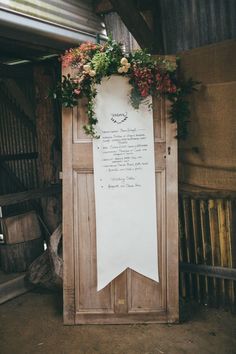 a sign with flowers on it in front of a wooden door that has writing on it