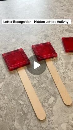 three wooden spatulas with red lids on them sitting on the floor next to each other