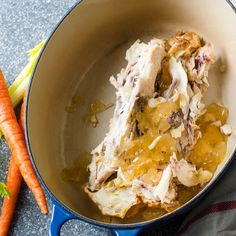 some food is being cooked in a pot with carrots and celery next to it