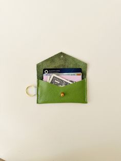 a green leather wallet with money sticking out of it's front pocket on a white surface