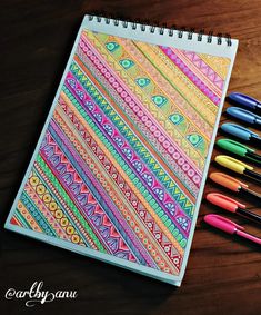 a notebook with markers and pens on top of it