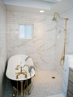 a bath tub sitting next to a window in a bathroom with white tiles on the walls