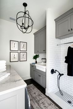 a white bathroom with gray cabinets and black accents on the shower head, sink, and towel rack