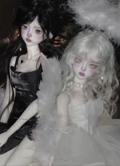 two dolls dressed in white and black sitting next to each other