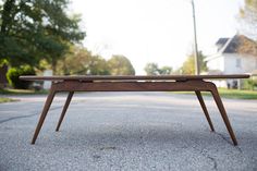 a wooden bench sitting on the side of a road in front of a tree filled street