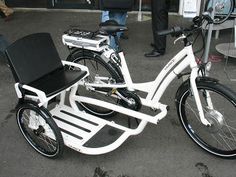 a white bicycle parked on the street next to people