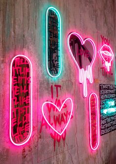 neon signs on the side of a building with graffiti written all over it and in different colors