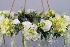 white flowers are hanging from the ceiling with twine ropes and greenery around them