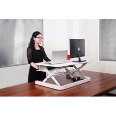 a woman standing in front of a desk with a computer on it