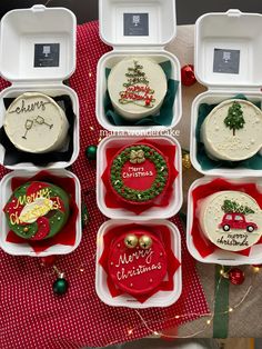 twelve decorated christmas cakes in plastic containers on a table