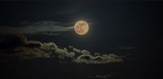 the full moon is shining brightly in the night sky above clouds and dark blue skies