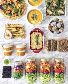 a table topped with lots of food and containers filled with different types of foods on top of it