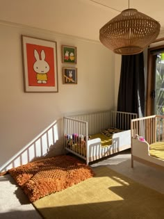 a baby's room with a crib, rug and pictures on the wall