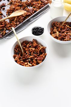 two white bowls filled with granola and blueberries