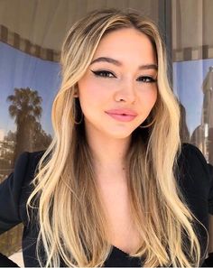 a woman with long blonde hair is posing for the camera