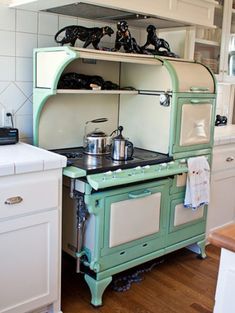 an old fashioned green stove top oven sitting in a kitchen next to a white counter