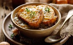 a bowl filled with food on top of a wooden table next to garlic and mushrooms