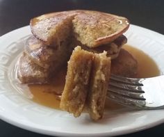 a white plate topped with pancakes covered in syrup