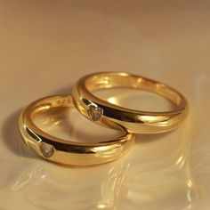 two gold wedding rings sitting on top of each other