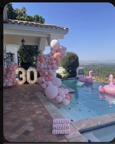 balloons are floating in the air next to a pool with pink flamingos on it