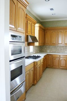 an empty kitchen with wooden cabinets and stainless steel stove top oven in the center area