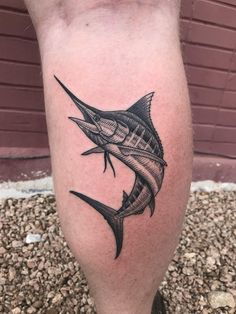 a man's leg with a black and white marlin fish tattoo on it