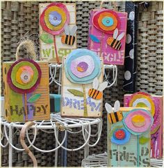 several cards with flowers on them are sitting on a rack in front of a wicker fence