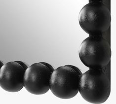 black balls are lined up in front of a mirror that is reflecting it's reflection