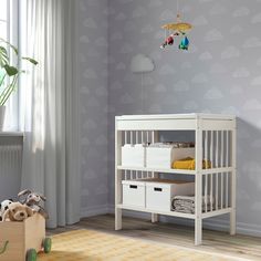 a baby's room with a crib, dresser and toy chest in it