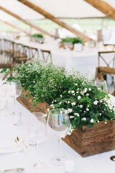 the table is set with wine glasses and greenery in wooden boxes on top of each other