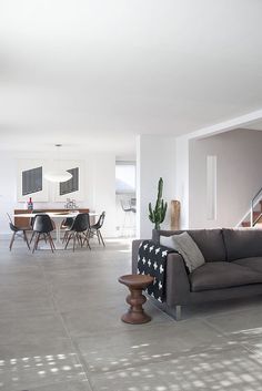 a living room filled with furniture next to a dining table and stairs in the background