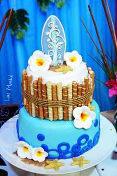 a blue cake with white flowers and bamboo decoration on it's top is sitting on a table