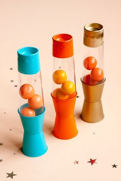 three vases with balls in them sitting on a table next to stars and confetti