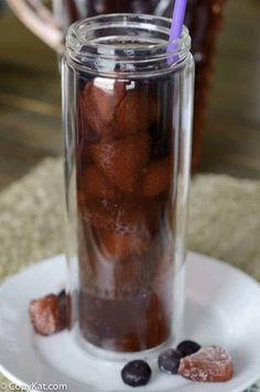 a glass jar filled with blueberries on top of a white plate