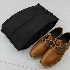 a pair of brown shoes sitting next to a black bag