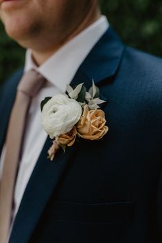 a man in a suit and tie with flowers on his lapel