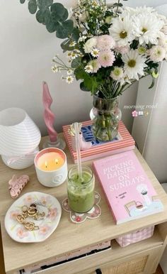 a small table with flowers and other items on it, such as a vase filled with daisies